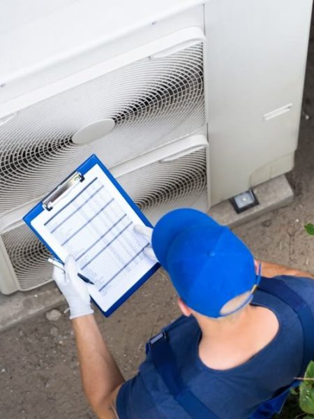 Technicians repairing outdoor HVAC unit on business roof